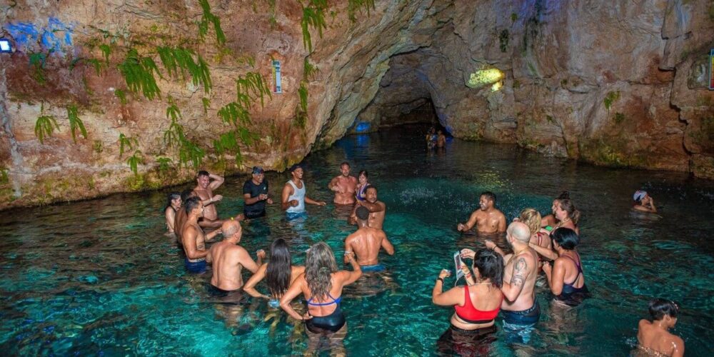 Refreshing cave swim in crystal clear water, surrounded by stunning rock formations and natural beauty, offering a serene and unique swimming experience in an underground cenote.