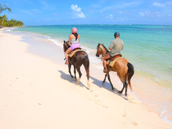 Scenic horse riding experience on the beach, with riders trotting along the shoreline, the gentle waves lapping at their feet, and the sun setting in the background, creating a tranquil and picturesque coastal adventure.