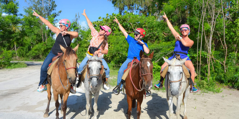 Scenic horse riding experience on the beach, with riders trotting along the shoreline, the gentle waves lapping at their feet, and the sun setting in the background, creating a tranquil and picturesque coastal adventure.