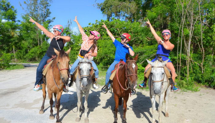 Scenic horse riding experience on the beach, with riders trotting along the shoreline, the gentle waves lapping at their feet, and the sun setting in the background, creating a tranquil and picturesque coastal adventure.