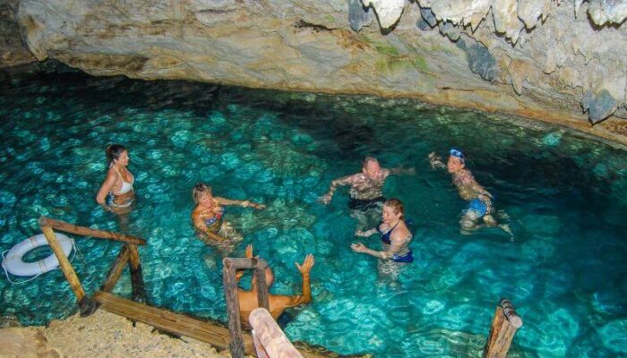 Refreshing cave swim in crystal clear water, surrounded by stunning rock formations and natural beauty, offering a serene and unique swimming experience in an underground cenote.