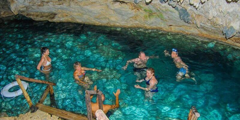 Refreshing cave swim in crystal clear water, surrounded by stunning rock formations and natural beauty, offering a serene and unique swimming experience in an underground cenote.