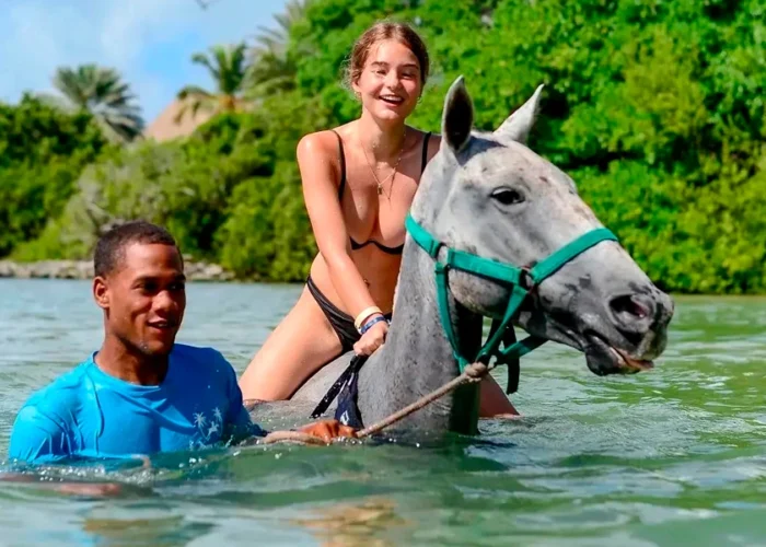 Scenic horse riding experience on the beach, with riders trotting along the shoreline, the gentle waves lapping at their feet, and the sun setting in the background, creating a tranquil and picturesque coastal adventure.