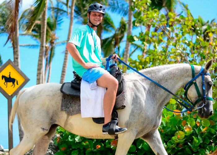 Scenic horse riding experience on the beach, with riders trotting along the shoreline, the gentle waves lapping at their feet, and the sun setting in the background, creating a tranquil and picturesque coastal adventure.
