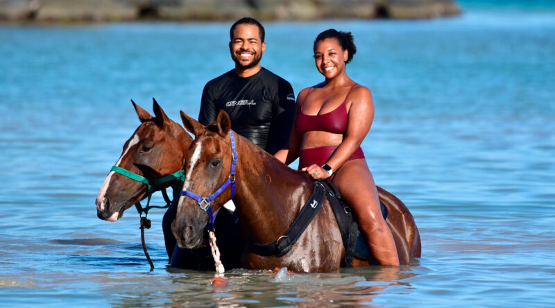 Scenic horse riding experience on the beach, with riders trotting along the shoreline, the gentle waves lapping at their feet, and the sun setting in the background, creating a tranquil and picturesque coastal adventure.