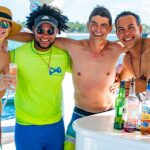 Vibrant party boat scene, with guests enjoying music, dancing, and refreshments on a lively boat deck, surrounded by open water and festive decorations, creating a fun and social atmosphere.