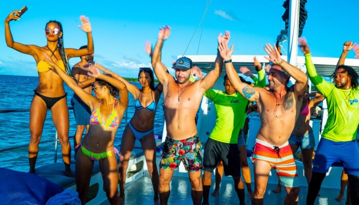 Vibrant party boat scene, with guests enjoying music, dancing, and refreshments on a lively boat deck, surrounded by open water and festive decorations, creating a fun and social atmosphere.