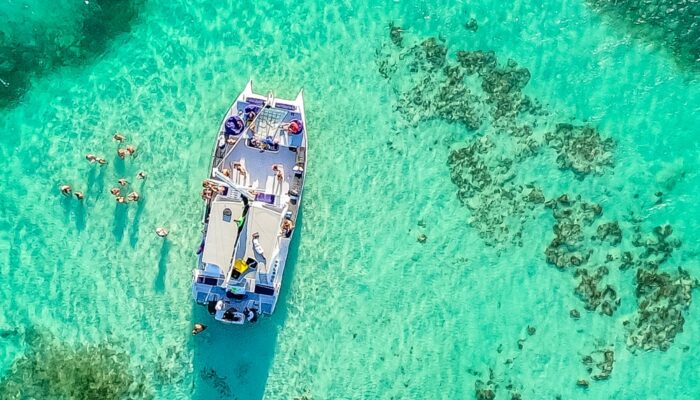 Vibrant party boat scene, with guests enjoying music, dancing, and refreshments on a lively boat deck, surrounded by open water and festive decorations, creating a fun and social atmosphere.