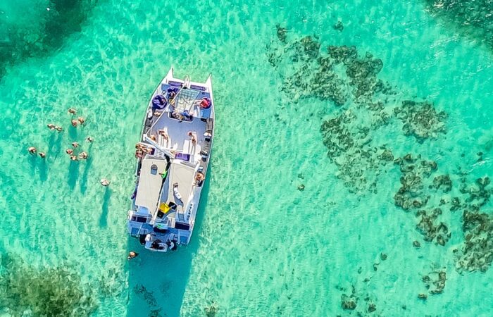 Vibrant party boat scene, with guests enjoying music, dancing, and refreshments on a lively boat deck, surrounded by open water and festive decorations, creating a fun and social atmosphere.