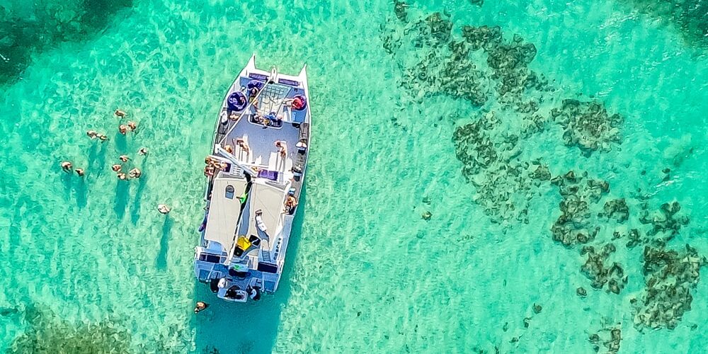 Vibrant party boat scene, with guests enjoying music, dancing, and refreshments on a lively boat deck, surrounded by open water and festive decorations, creating a fun and social atmosphere.