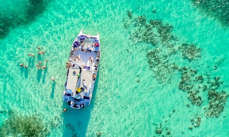 Vibrant party boat scene, with guests enjoying music, dancing, and refreshments on a lively boat deck, surrounded by open water and festive decorations, creating a fun and social atmosphere.