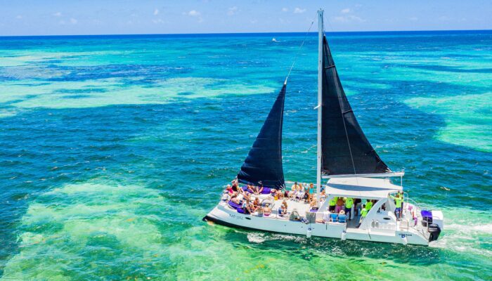 Vibrant party boat scene, with guests enjoying music, dancing, and refreshments on a lively boat deck, surrounded by open water and festive decorations, creating a fun and social atmosphere.