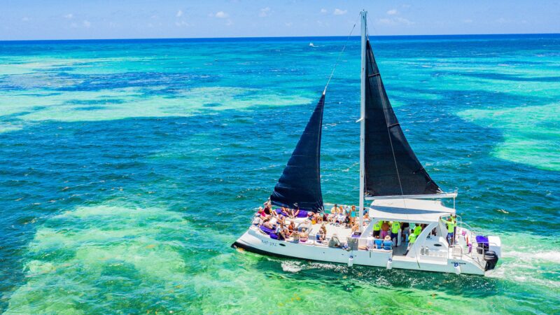 Vibrant party boat scene, with guests enjoying music, dancing, and refreshments on a lively boat deck, surrounded by open water and festive decorations, creating a fun and social atmosphere.