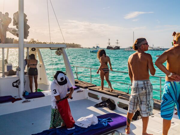 Vibrant party boat scene, with guests enjoying music, dancing, and refreshments on a lively boat deck, surrounded by open water and festive decorations, creating a fun and social atmosphere.