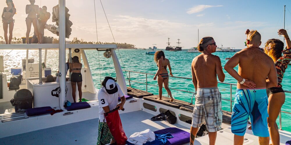 Vibrant party boat scene, with guests enjoying music, dancing, and refreshments on a lively boat deck, surrounded by open water and festive decorations, creating a fun and social atmosphere.