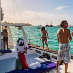 Vibrant party boat scene, with guests enjoying music, dancing, and refreshments on a lively boat deck, surrounded by open water and festive decorations, creating a fun and social atmosphere.