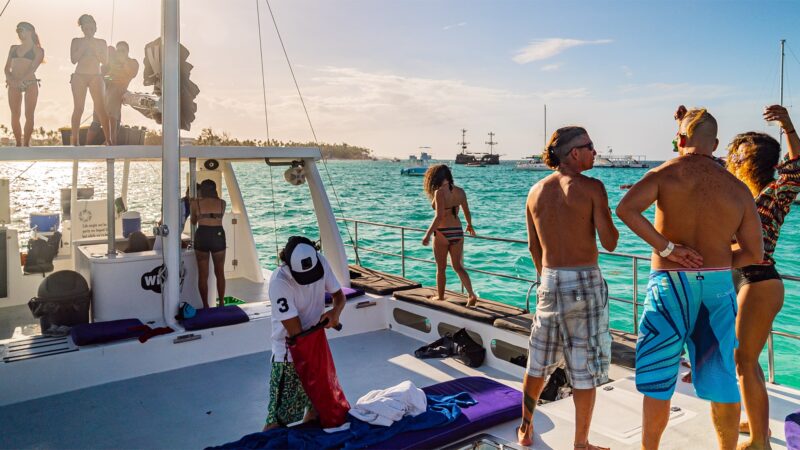 Vibrant party boat scene, with guests enjoying music, dancing, and refreshments on a lively boat deck, surrounded by open water and festive decorations, creating a fun and social atmosphere.