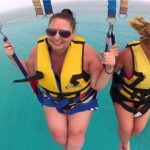 Thrilling parasailing experience, with individuals soaring high above the water while securely harnessed to a colorful parachute, enjoying breathtaking aerial views and the excitement of gliding over the ocean.