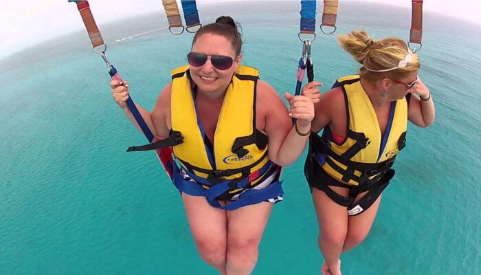 Thrilling parasailing experience, with individuals soaring high above the water while securely harnessed to a colorful parachute, enjoying breathtaking aerial views and the excitement of gliding over the ocean.