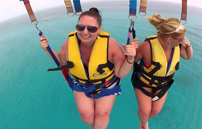 Thrilling parasailing experience, with individuals soaring high above the water while securely harnessed to a colorful parachute, enjoying breathtaking aerial views and the excitement of gliding over the ocean.