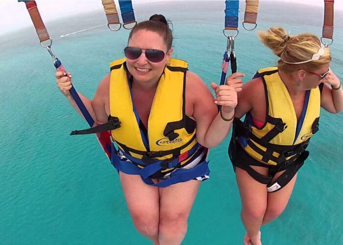 Thrilling parasailing experience, with individuals soaring high above the water while securely harnessed to a colorful parachute, enjoying breathtaking aerial views and the excitement of gliding over the ocean.