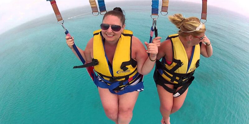 Thrilling parasailing experience, with individuals soaring high above the water while securely harnessed to a colorful parachute, enjoying breathtaking aerial views and the excitement of gliding over the ocean.