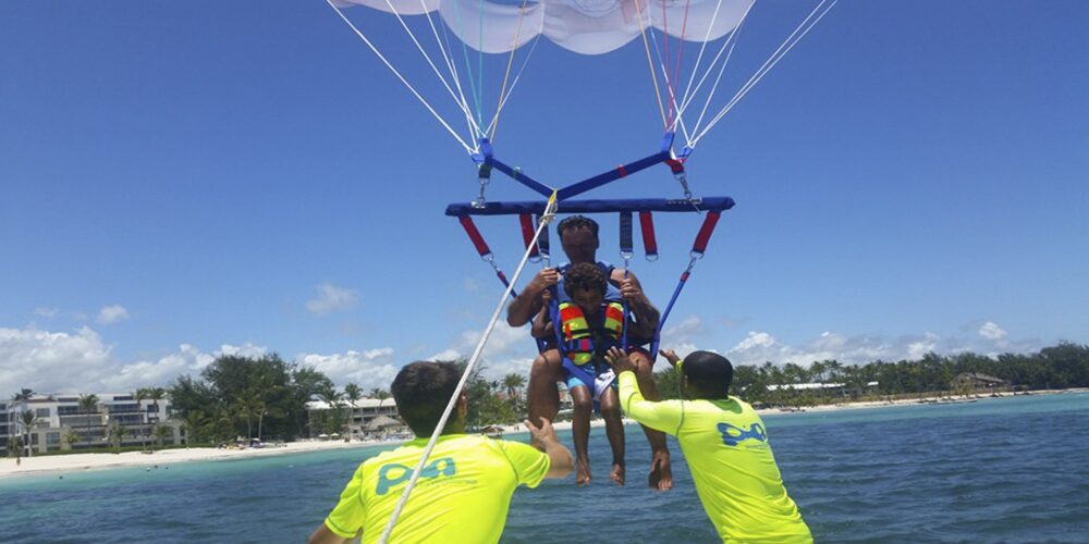 Thrilling parasailing experience, with individuals soaring high above the water while securely harnessed to a colorful parachute, enjoying breathtaking aerial views and the excitement of gliding over the ocean.