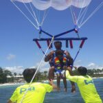 Thrilling parasailing experience, with individuals soaring high above the water while securely harnessed to a colorful parachute, enjoying breathtaking aerial views and the excitement of gliding over the ocean.