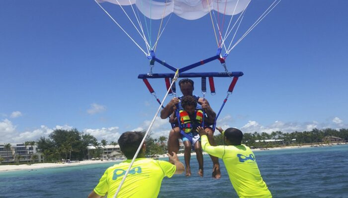 Thrilling parasailing experience, with individuals soaring high above the water while securely harnessed to a colorful parachute, enjoying breathtaking aerial views and the excitement of gliding over the ocean.