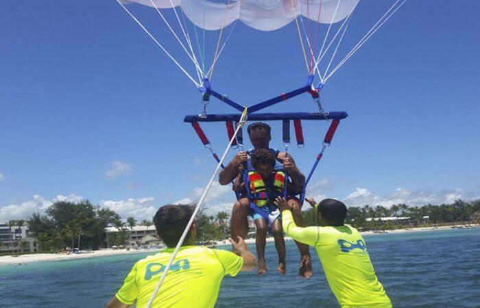 Thrilling parasailing experience, with individuals soaring high above the water while securely harnessed to a colorful parachute, enjoying breathtaking aerial views and the excitement of gliding over the ocean.
