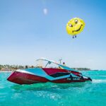 Thrilling parasailing experience, with individuals soaring high above the water while securely harnessed to a colorful parachute, enjoying breathtaking aerial views and the excitement of gliding over the ocean.