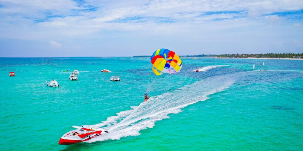 Thrilling parasailing experience, with individuals soaring high above the water while securely harnessed to a colorful parachute, enjoying breathtaking aerial views and the excitement of gliding over the ocean.