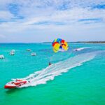 Thrilling parasailing experience, with individuals soaring high above the water while securely harnessed to a colorful parachute, enjoying breathtaking aerial views and the excitement of gliding over the ocean.