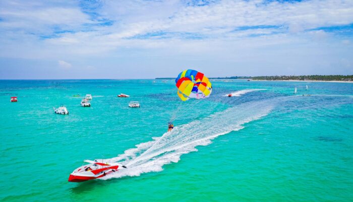 Thrilling parasailing experience, with individuals soaring high above the water while securely harnessed to a colorful parachute, enjoying breathtaking aerial views and the excitement of gliding over the ocean.