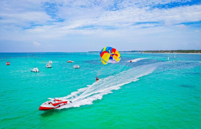Thrilling parasailing experience, with individuals soaring high above the water while securely harnessed to a colorful parachute, enjoying breathtaking aerial views and the excitement of gliding over the ocean.