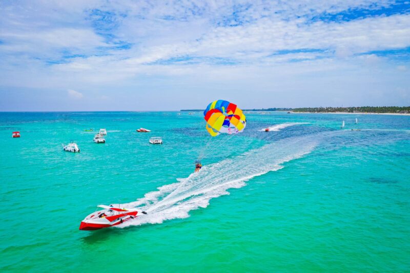 Thrilling parasailing experience, with individuals soaring high above the water while securely harnessed to a colorful parachute, enjoying breathtaking aerial views and the excitement of gliding over the ocean.