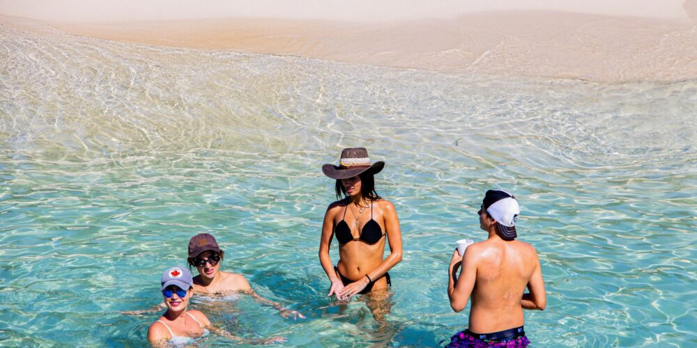 Sunbathers and beachgoers enjoying the pristine white sands and crystal-clear waters of Catalina Beach, relaxing under umbrellas, swimming, and engaging in beach activities in a picturesque tropical setting.