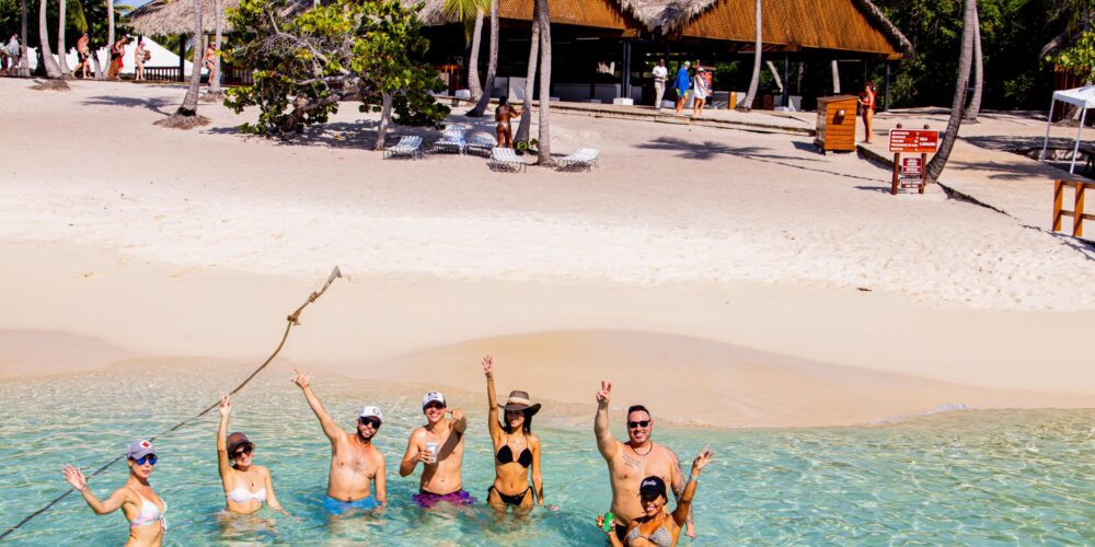 Sunbathers and beachgoers enjoying the pristine white sands and crystal-clear waters of Catalina Beach, relaxing under umbrellas, swimming, and engaging in beach activities in a picturesque tropical setting.