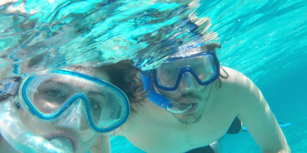 Participants snorkeling in clear, turquoise waters, wearing masks and snorkels to explore vibrant coral reefs and colorful marine life, enjoying an underwater adventure in a tropical setting.