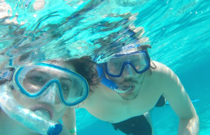 Participants snorkeling in clear, turquoise waters, wearing masks and snorkels to explore vibrant coral reefs and colorful marine life, enjoying an underwater adventure in a tropical setting.