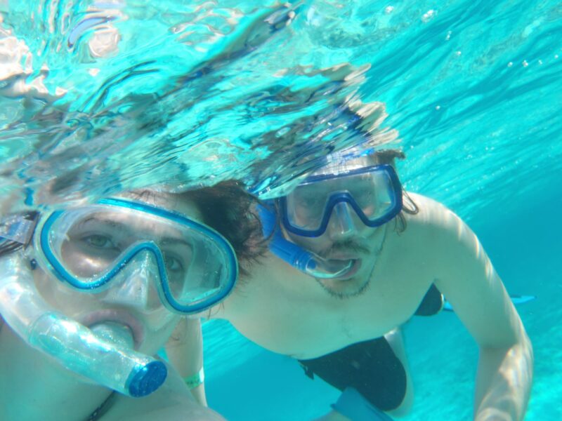 Participants snorkeling in clear, turquoise waters, wearing masks and snorkels to explore vibrant coral reefs and colorful marine life, enjoying an underwater adventure in a tropical setting.