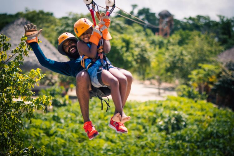 Participants ziplining through treetops with panoramic views of lush landscapes.