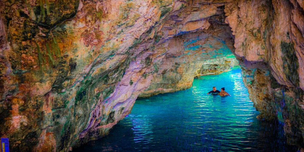 Refreshing cave swim in crystal clear water, surrounded by stunning rock formations and natural beauty, offering a serene and unique swimming experience in an underground cenote.