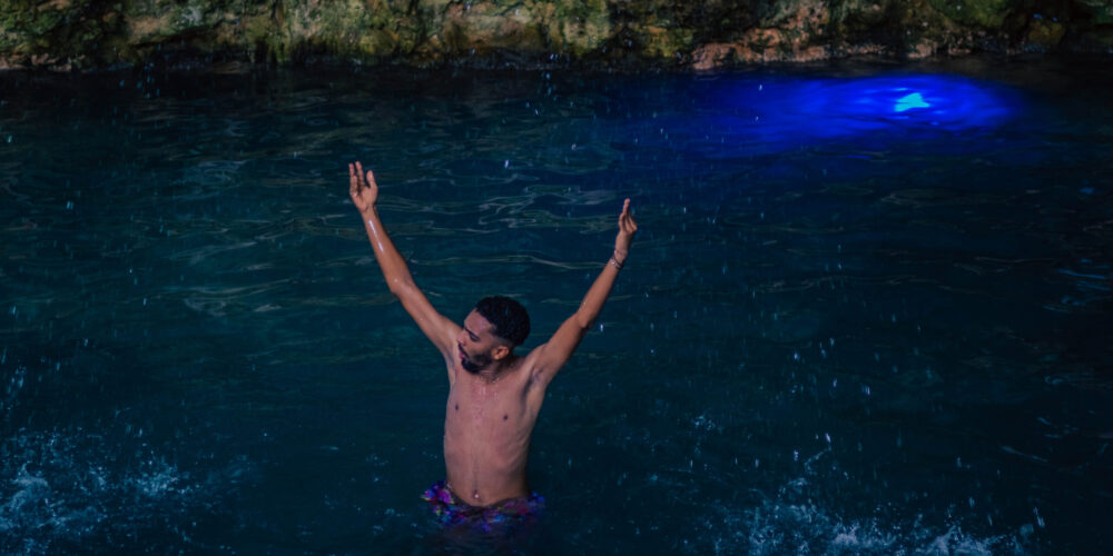 Refreshing cave swim in crystal clear water, surrounded by stunning rock formations and natural beauty, offering a serene and unique swimming experience in an underground cenote.